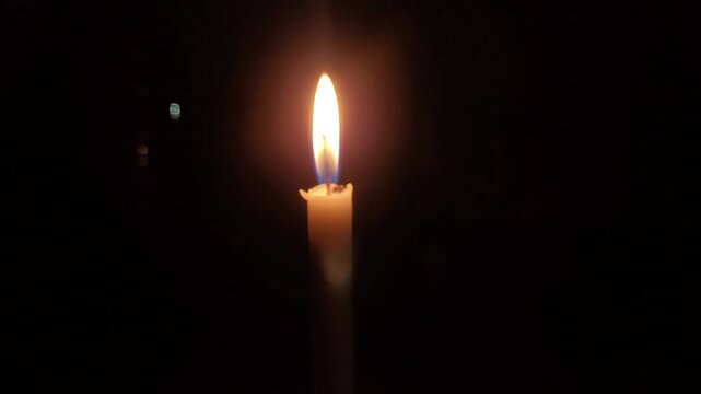 burning candle on black background