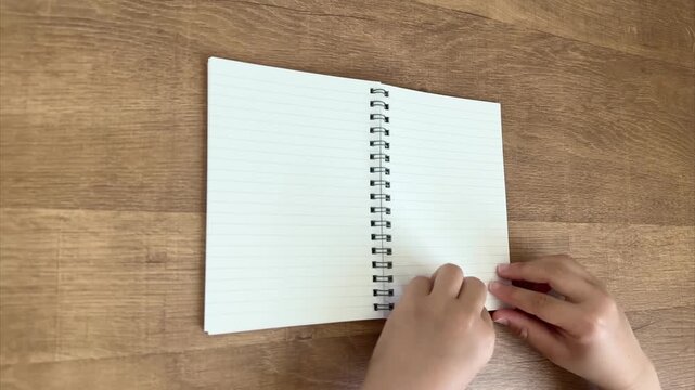 Child Hands Turning Two Pages of Open Ring Notebook, 4K