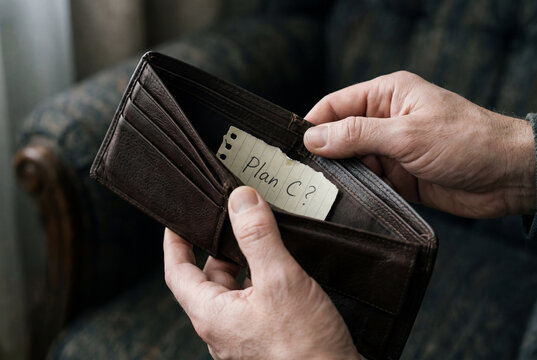 Man holding an open empty wallet with a handwritten note