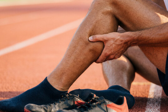 Male runner holding leg due to sudden muscle calf cramp