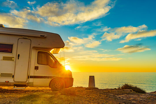 Warm sunset view at the beach with a camper van parked along the shore by the water