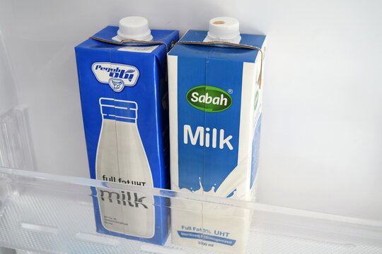 Two cartons of Pegah and Sabah UHT milk on a shelf inside a refrigerator 