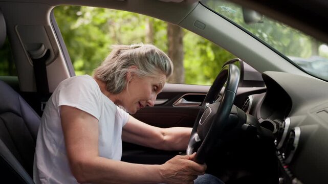 Old aged elderly Caucasian woman trying start driving car broken retired senior female driver has problem with auto motor mature lady difficulty with modern electric automobile vehicle transport fail