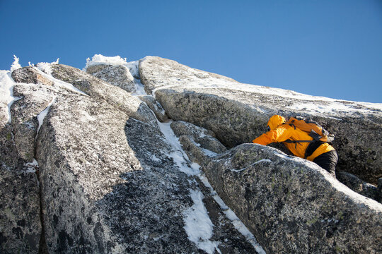 Mountain climber ascends a snowy rock face