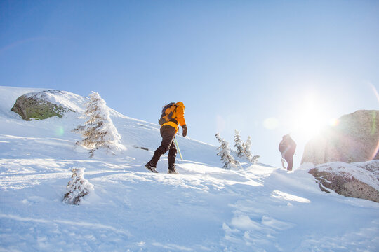 Two hikers trek up a snowy mountain slope