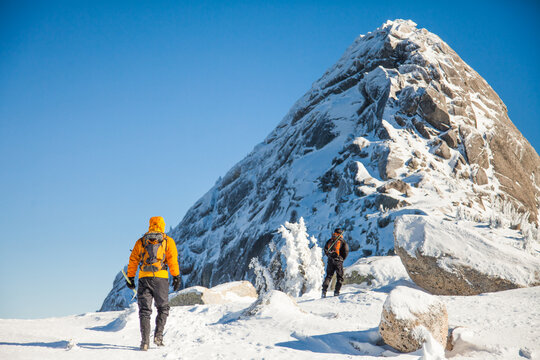 Two men hiking toward a snowy mountain peak