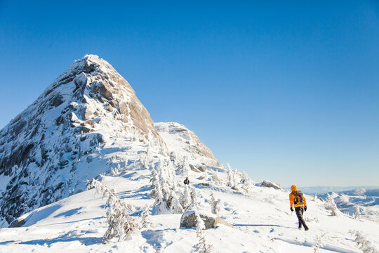 Hiker trekking across a sunny snow covered mountain