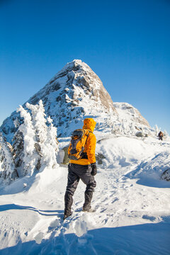 Hiker in yellow jacket ascends snowy mountain