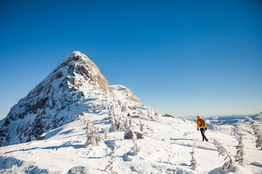 Person hikes across a snowy mountain landscape