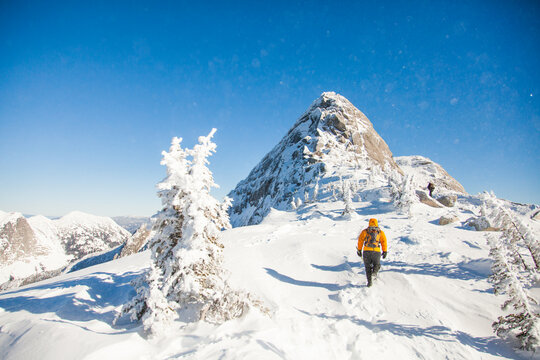 Hiker trekking through deep snow on a sunny mountain