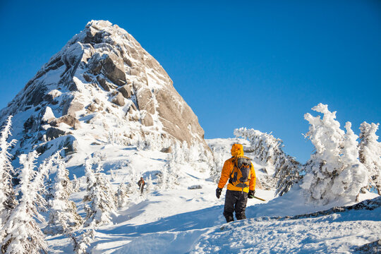 Hiker ascends snowy mountain on a sunny day