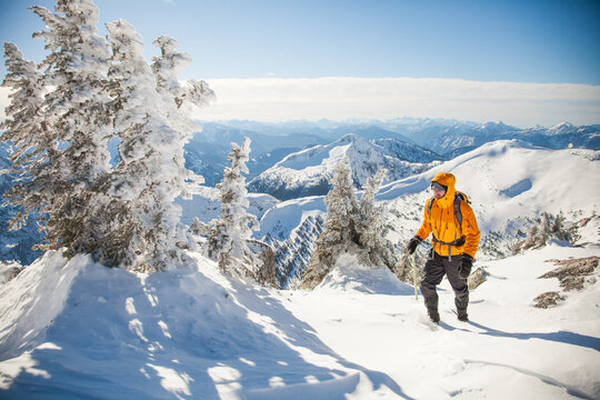 Man hikes up a snowy mountain on a sunny day
