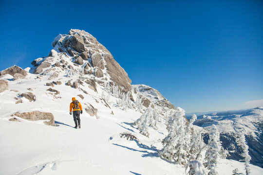 Person hiking up a snowy mountain on a clear day