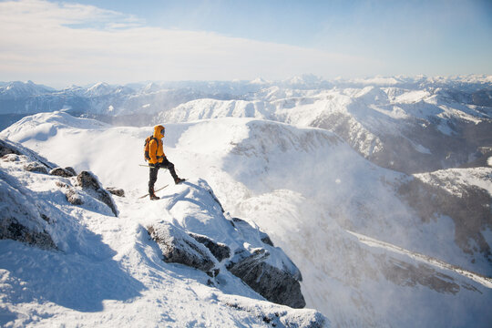 Winter mountaineer stands on a windy summit