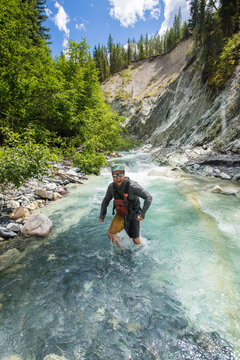 Joyful man splashing through a glacial mountain river