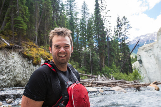 Happy man wearing life jacket by a forest river
