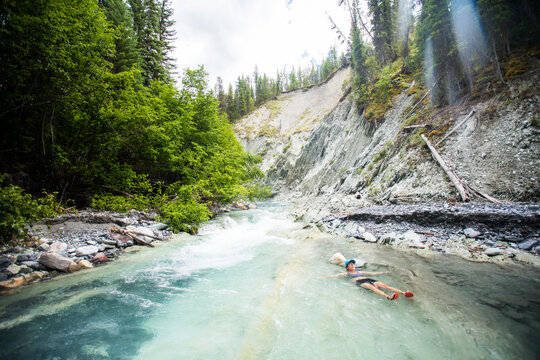 Woman floating peacefully in a turquoise glacial river