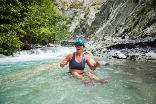 Surprised woman sitting in a cold mountain river