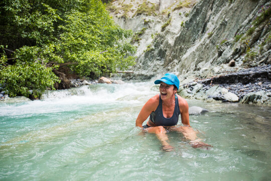 Laughing woman enjoying a cold plunge in a river