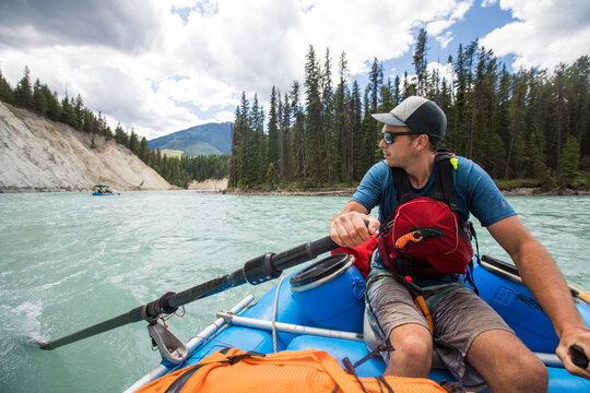 Man rowing inflatable raft on a scenic glacial river
