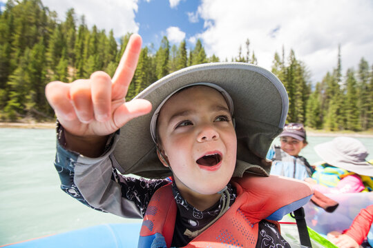 Excited young boy making a hand sign on a river trip