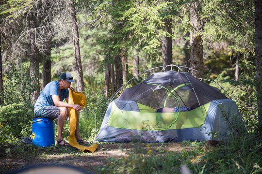 Man inflates sleeping mat at a woodland campsite