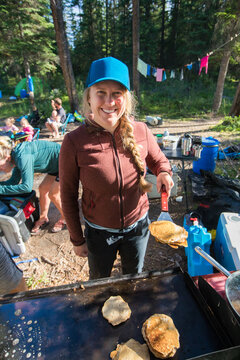 Smiling woman cooks breakfast pancakes while camping