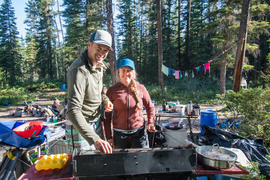 Happy couple cooks breakfast at a forest campsite