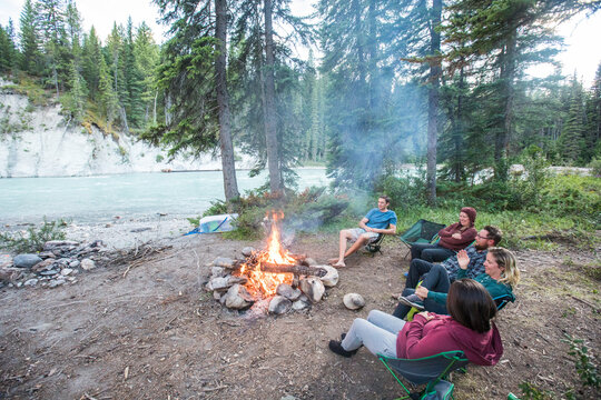 Friends chilling by a campfire next to a river