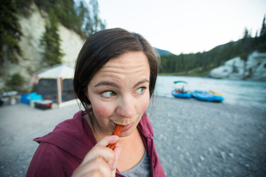 Candid woman eating a jerky snack while camping
