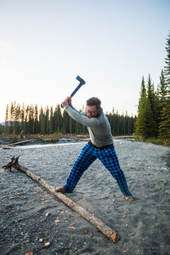 Man chopping wood with an axe in plaid pajamas