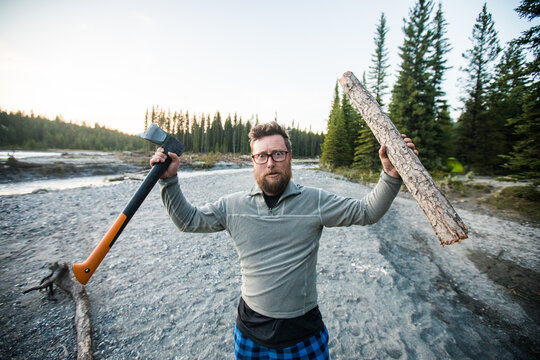 Funny bearded man holds up axe and log
