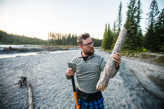 Man with an axe holding a log for firewood