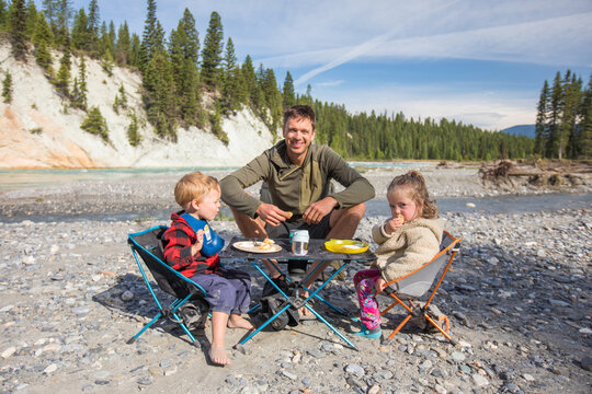 Father and kids having a picnic by a mountain river