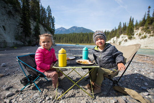 Two children eating at a riverside campsite