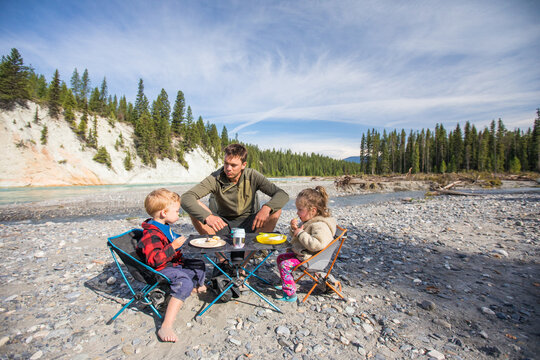 Dad and kids enjoy a snack while camping outdoors