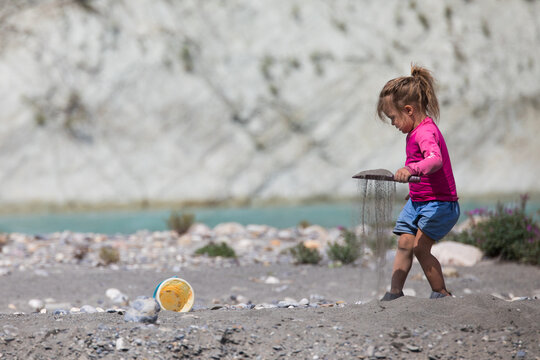 Young girl letting sand fall from a shovel