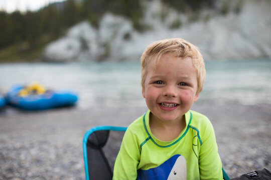 Blond toddler boy smiling happily by a river