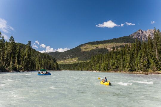 People rafting and kayaking on a scenic mountain river