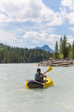 Woman paddling packraft on a scenic mountain river
