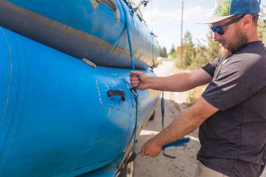 Man securing inflatable raft with tie down straps