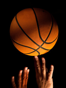 Hands reaching for a basketball against a black background