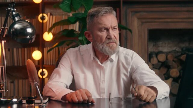 Puzzled Caucasian old aged business man thinking looking at photo in frame on office table senior aging businessman think taking off glasses elderly male entrepreneur worried hesitate deep in thoughts