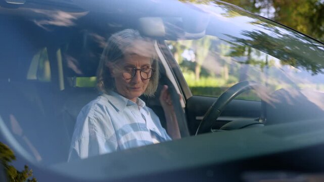 Serious confident Caucasian retired old woman sitting inside own renting car fastening seat belt senior mature female driver client automobile buying test drive in city ready to driving granny in auto