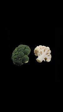 Rotating cauliflower and broccoli on a black background, vertical video featuring fresh healthy vegetables, clean food presentation and minimalist culinary concept