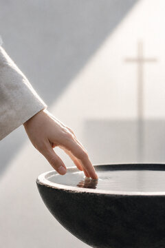 Hand touching holy water font before church prayer