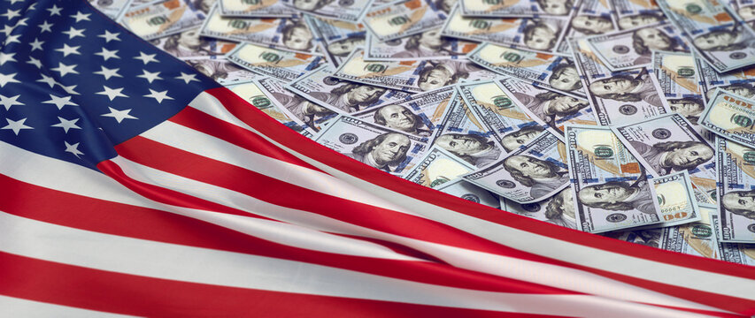 Pile of US dollars with American flag. Symbol of US federal budget, public finance, economic policy, taxation, debt and government spending