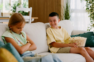 Sibling rivalry with boy teasing upset girl on sofa © djile