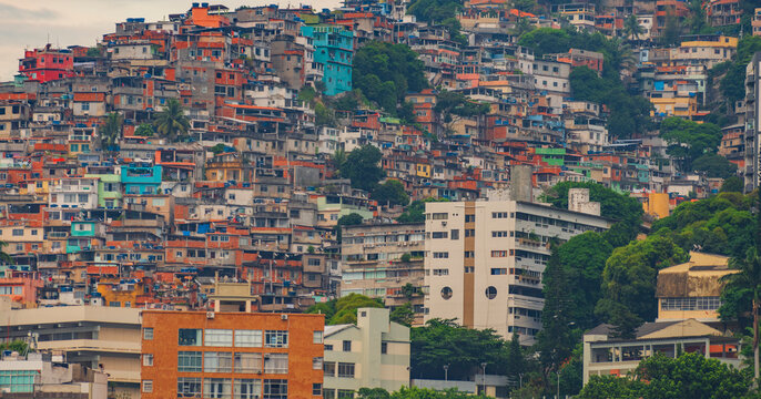 Colorful favela houses crowding steep hillside above modern city buildings