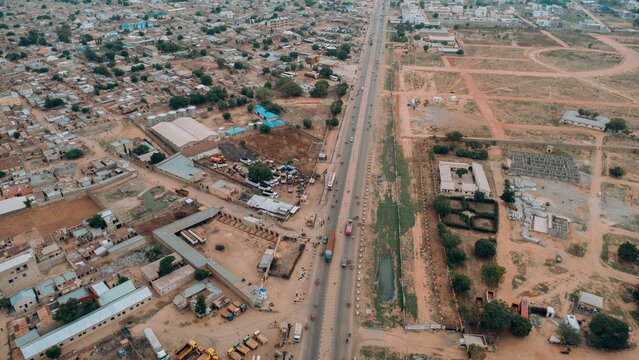 Farawa, Nigeria - 17 June 2026: Aerial view of a main road passing through the Farawa district, showing dense residential housing on one side and developing land plots on the other.